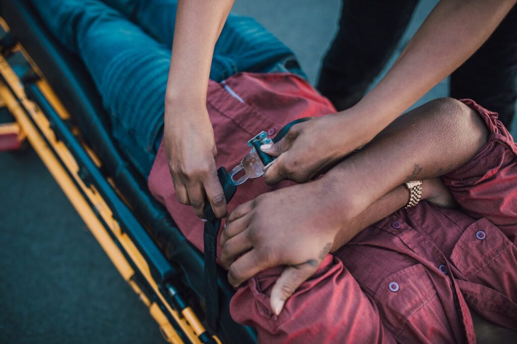 pexels-photo-6520167 Close-up of a person securing an injured individual on a stretcher, providing emergency care.